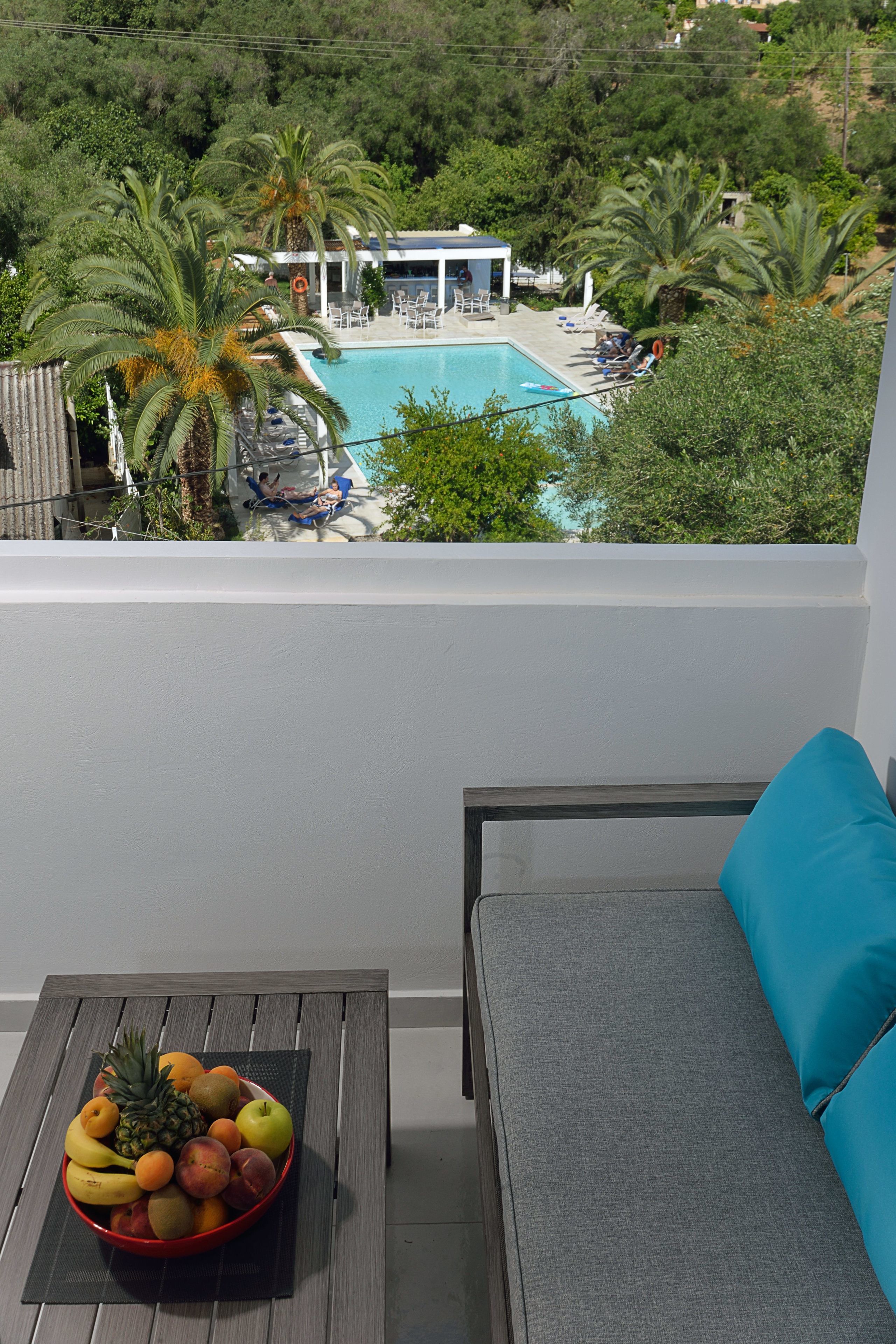 A balcony with a pool, a fruit bowl, and a view of the pool area.