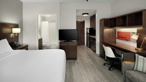 A hotel room with a bed, desk, chair, TV, and kitchenette. - Towneplace Suites Anchorage Midtown (Anchorage)