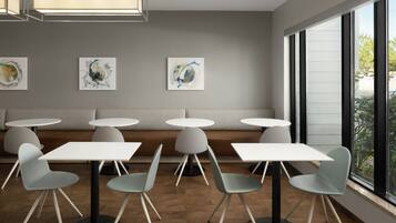 Un intérieur moderne avec des tables et des chaises rondes, un canapé et des œuvres d’art abstraites accrochées au mur.
