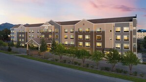 A multi-story hotel with a modern design, featuring a central entrance and multiple balconies. - Towneplace Suites Anchorage Midtown (Anchorage)