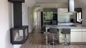 Et moderne køkken med en central ø, rustfrie hårde hvidevarer og et stort vindue, der giver naturligt lys.