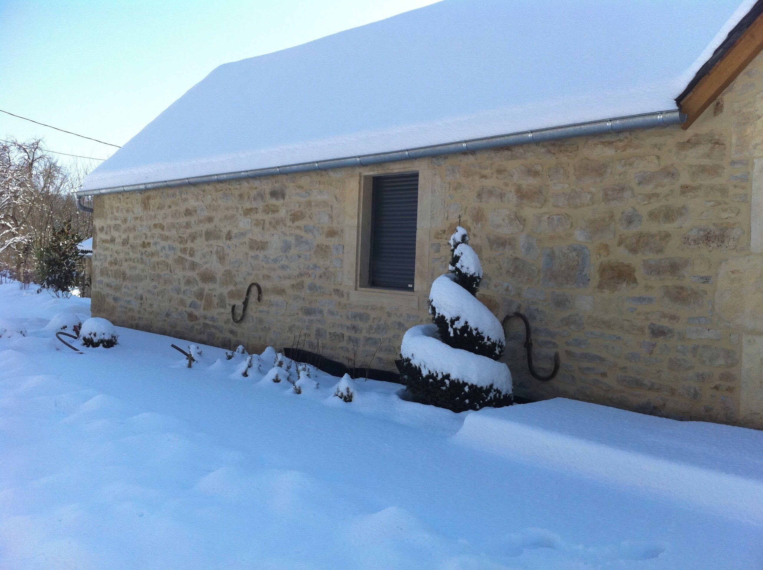 Un bâtiment en pierre avec un toit enneigé et une petite fenêtre.
