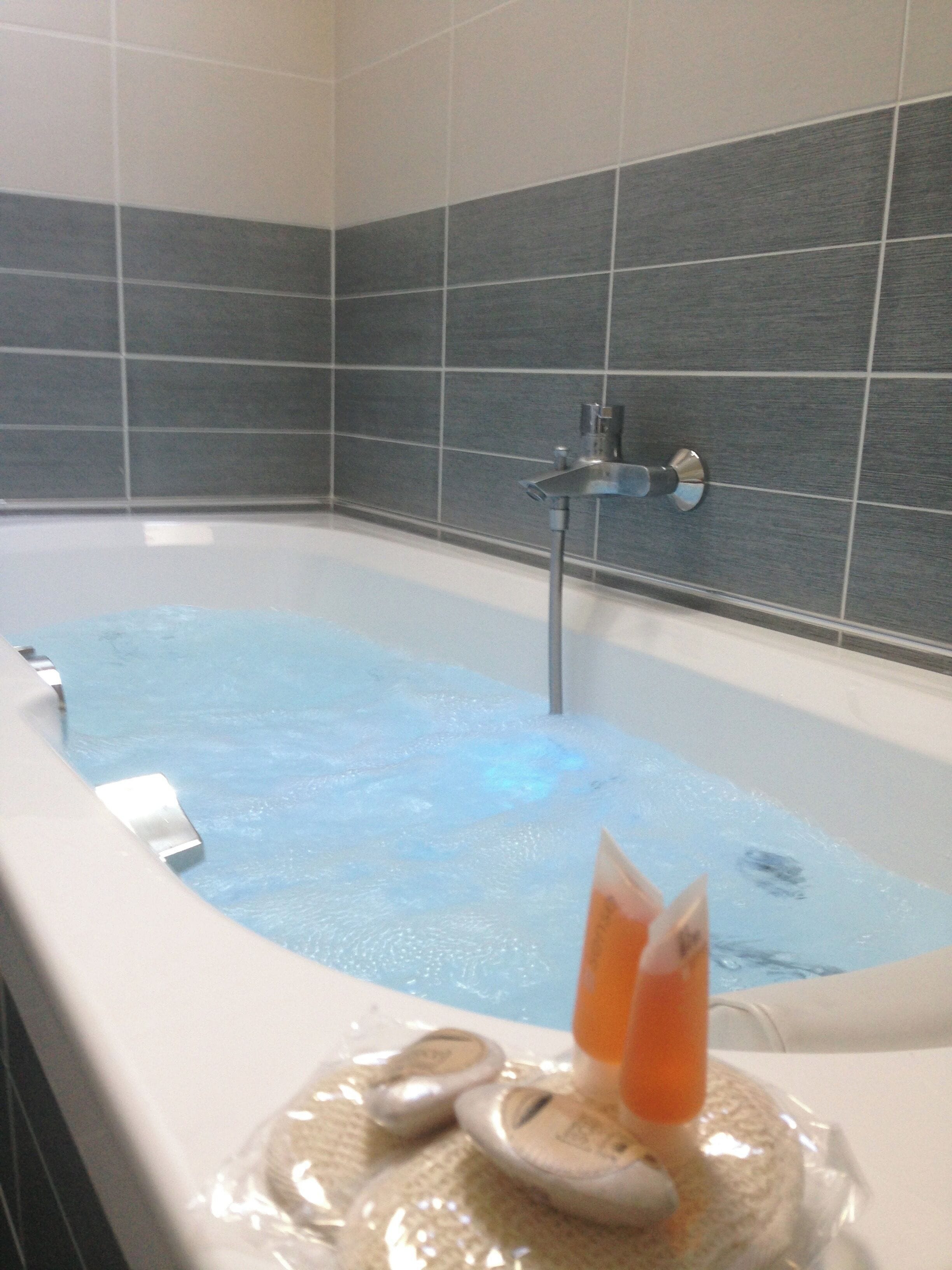 Une baignoire avec un robinet et une bouteille de shampoing.