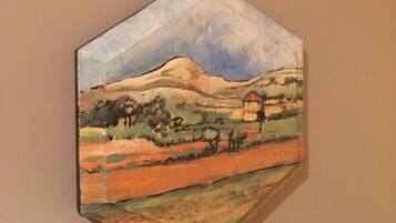 A hexagonal painting of a rural landscape with a mountain and houses, mounted on a wall above a number '2'.
