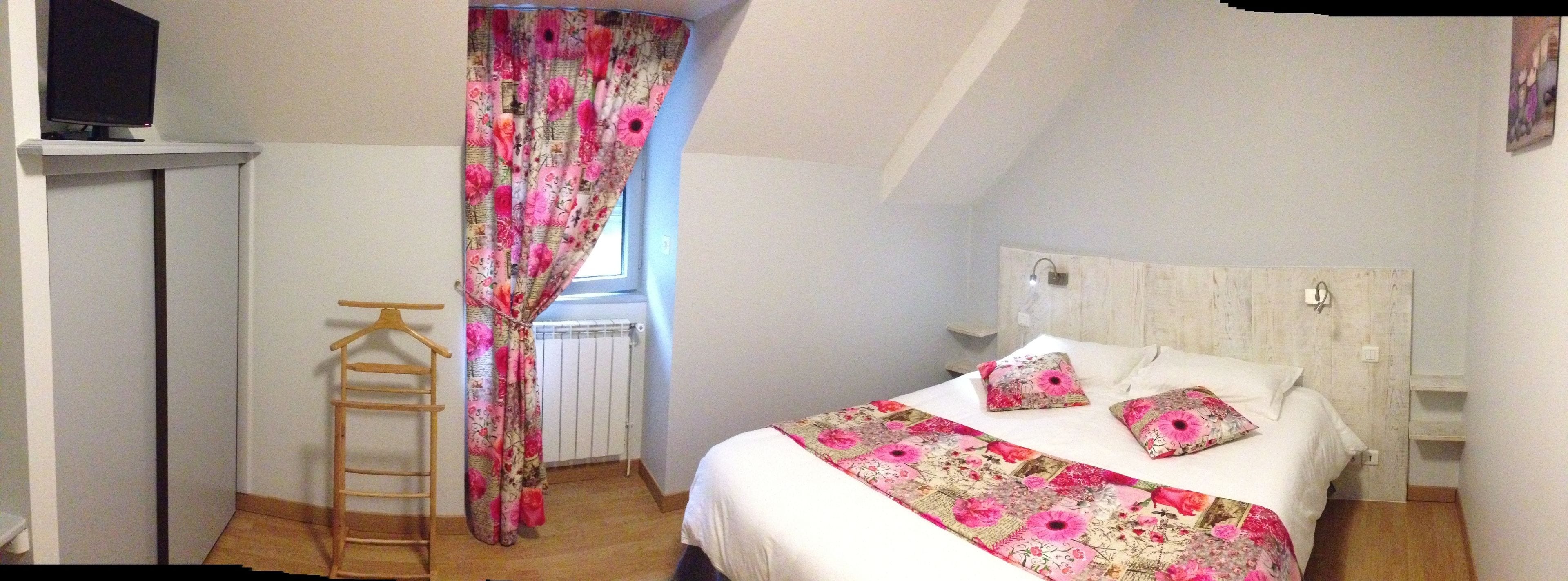 A bedroom with a bed, a wooden ladder, a radiator, and a window with floral curtains.
