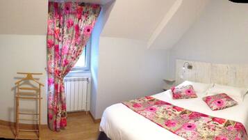 A bedroom with a bed, a wooden ladder, a radiator, and a window with floral curtains.