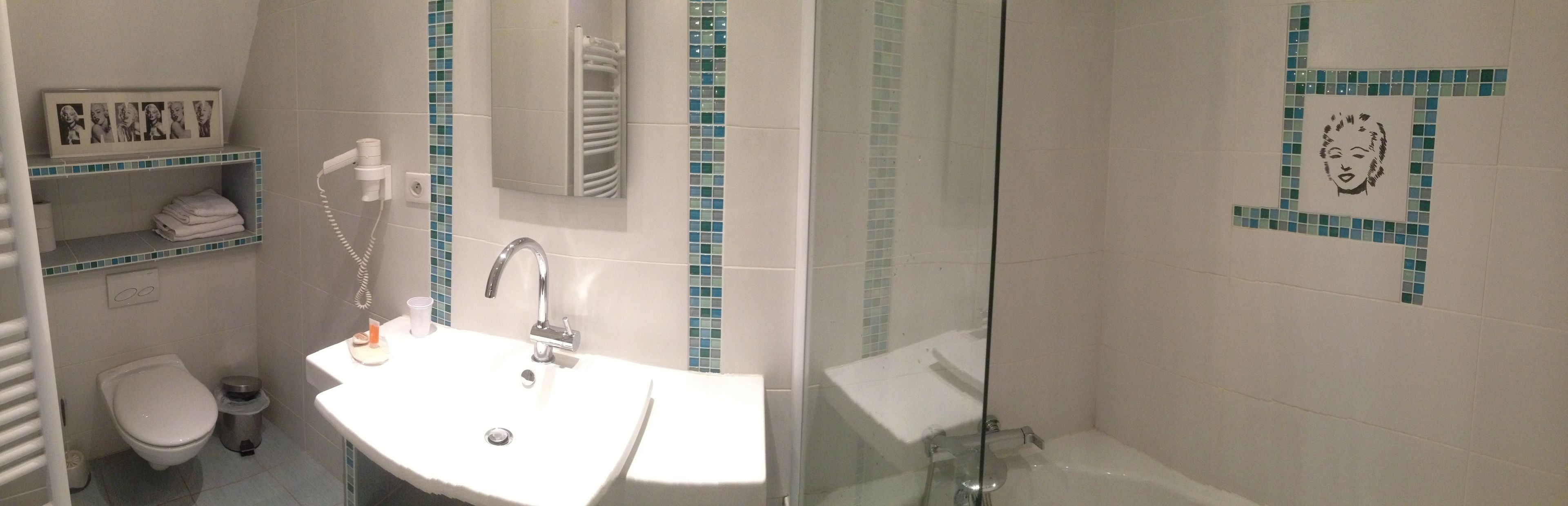 A bathroom with a white sink, a mirror, a towel rack, and a glass shower enclosure.