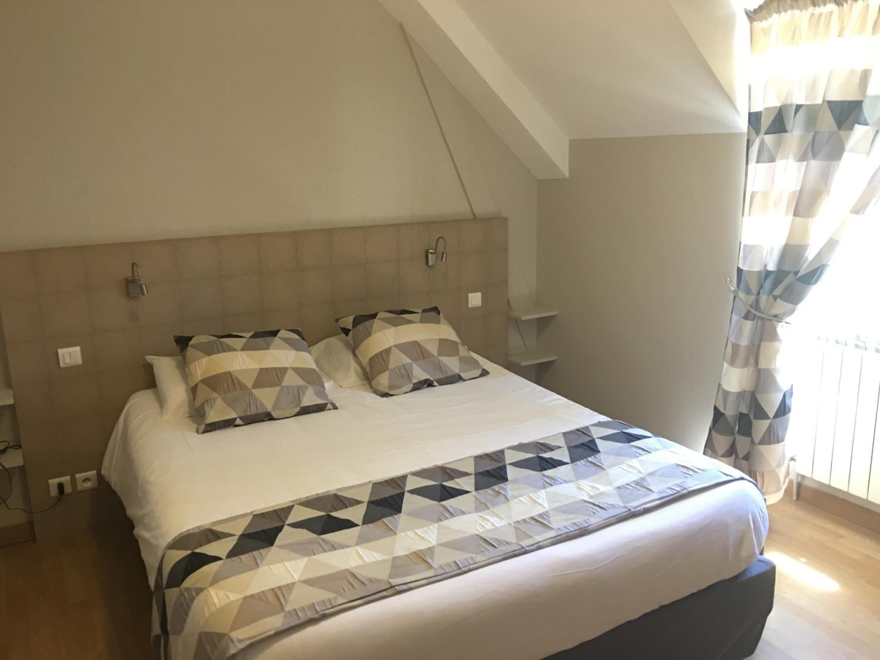 Un dormitorio con una cama grande, cabecera y una ventana con cortinas.