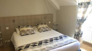 Un dormitorio con una cama grande, cabecera y una ventana con cortinas.