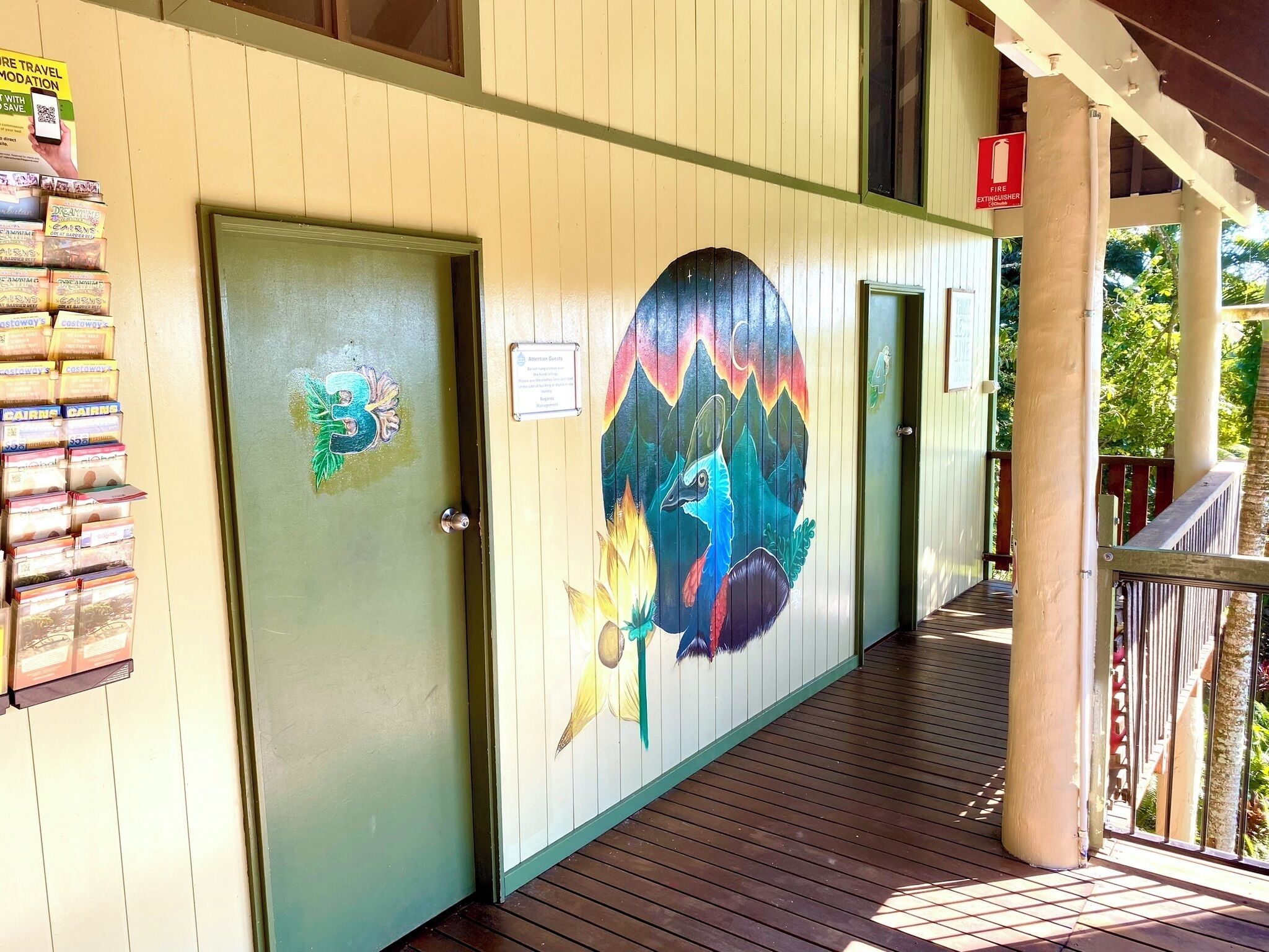 Un bâtiment avec une porte verte, une fresque colorée sur le mur et une terrasse en bois.