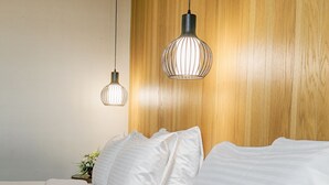A bedroom with two beds, wooden headboard, and pendant lights.