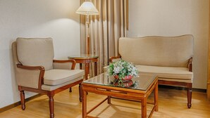 A room with a wooden coffee table, two armchairs, a sofa, and a floor lamp.