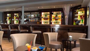 Een bar met zitplaatsen, een toog en verschillende flessen en glazen.