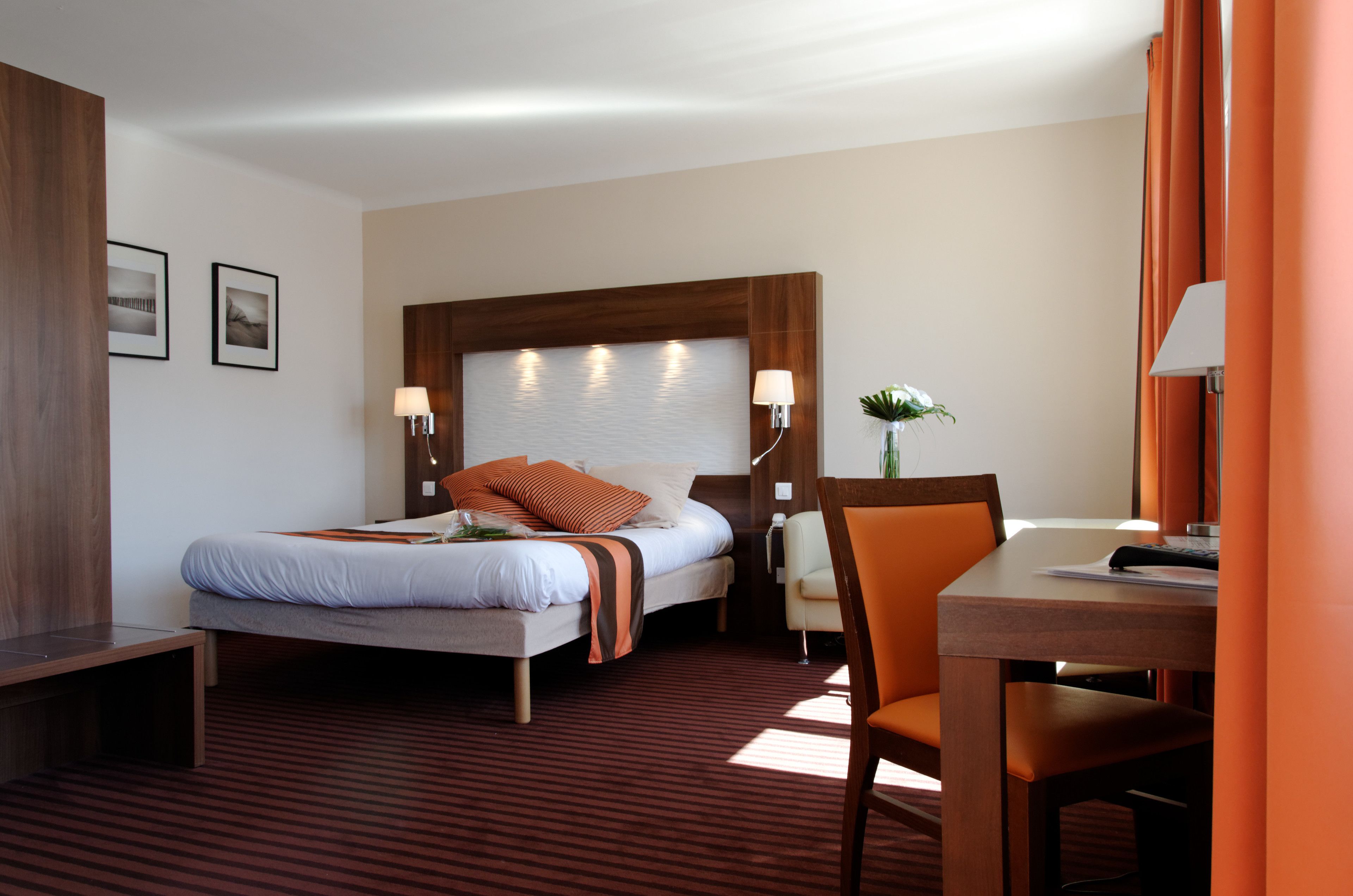 Una habitación de hotel con cama, mesita de noche, silla y escritorio con lámpara.