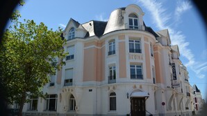 Een historisch gebouw met een gebogen gevel en een opvallend bord met de tekst 'REGINA HOTEL', in klassieke bouwstijl.