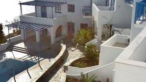 A white building with blue accents, a stone pathway, and a view of the sea. - Arkas Inn (Paros)