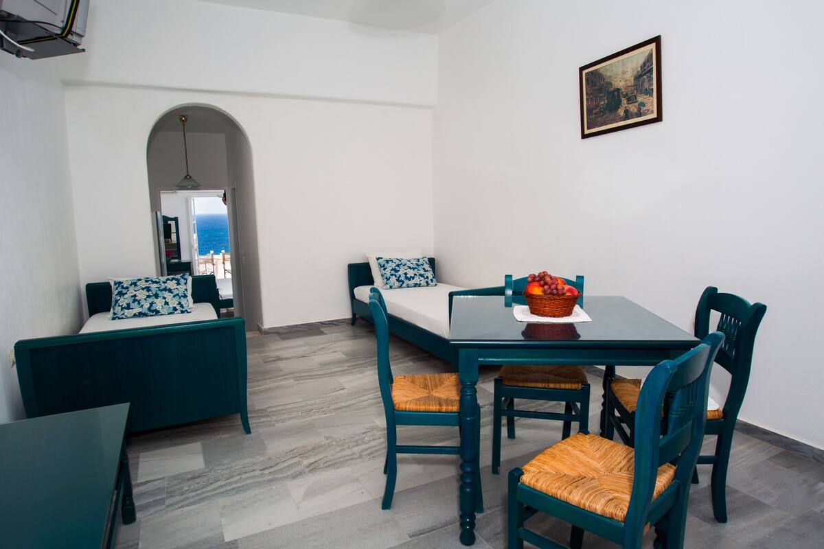 A dining area with a table, chairs, and a sofa.