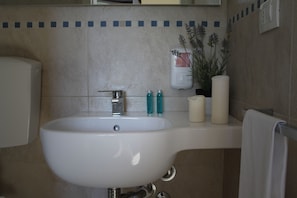 A bathroom with a white sink, a mirror, a towel rack, and toiletries on the counter. - Torre del Mare (Ispica)