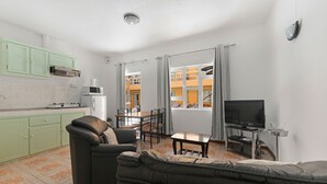 Um espaço de estar compacto com cozinha compacta, um sofá, uma mesa de jantar e uma televisão.