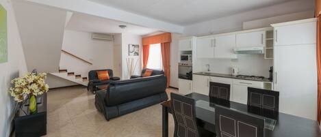 Un apartamento moderno con sala de estar, comedor y cocina. Una escalera conduce a un nivel superior.