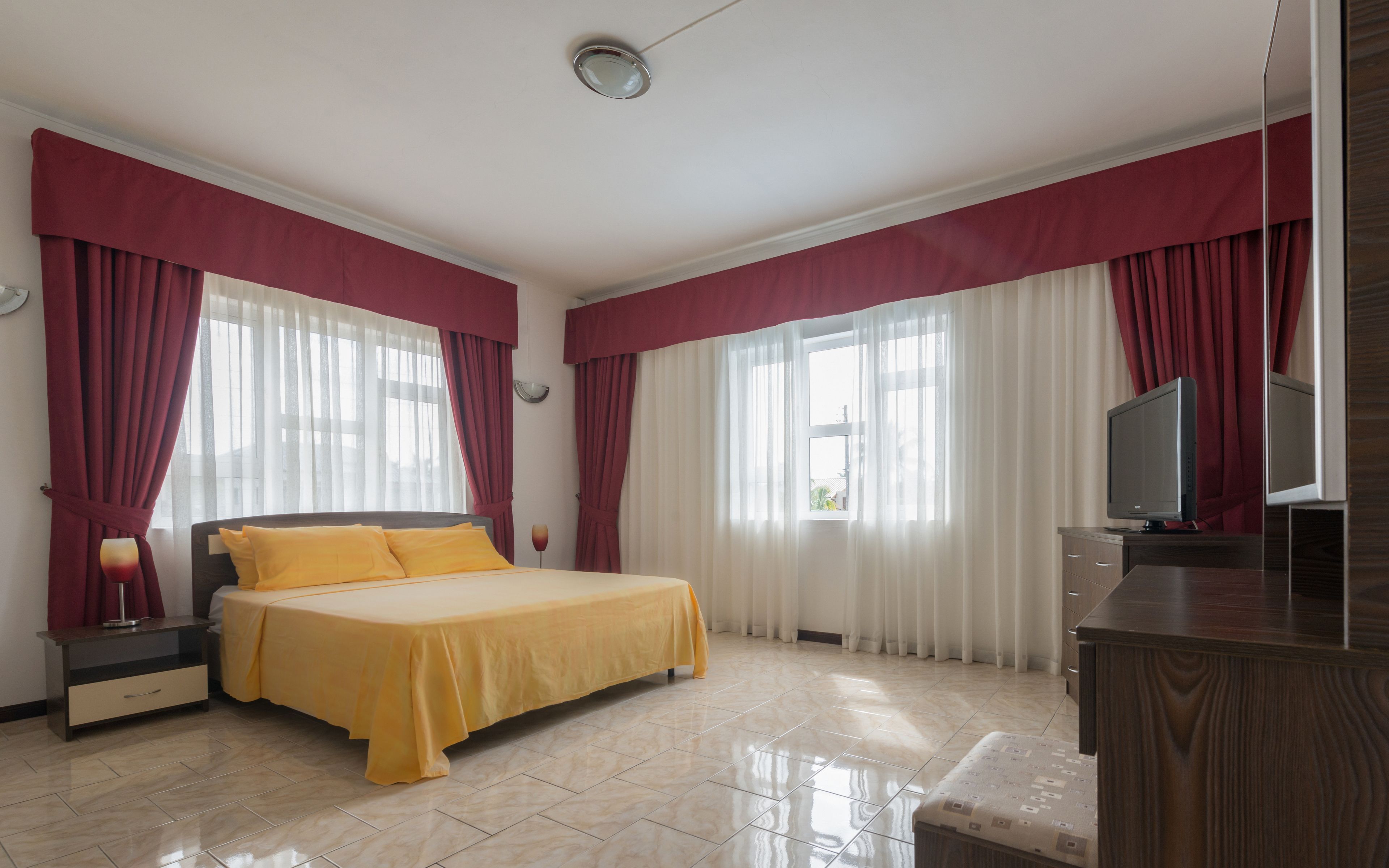 A hotel room with a bed, a TV, a nightstand, and a dresser.