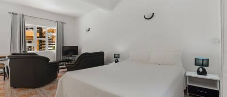 A hotel room with a large bed, a desk with a computer, a TV, and a chair.