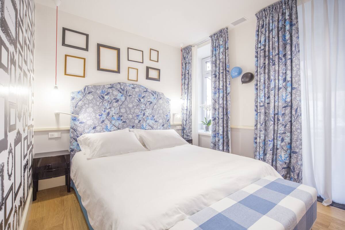 A neatly arranged bedroom with a bed, a bedside table, and a wall-mounted lamp.