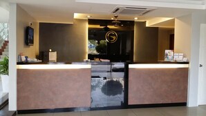Una mesa de recepción con un logotipo grande, un televisor de pantalla plana y una pequeña planta.