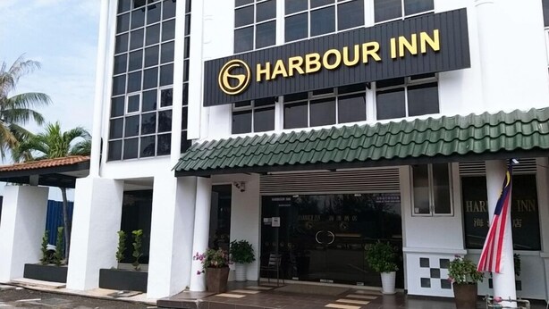 Edificio del Harbour Inn con un letrero llamativo, ventanas amplias y techo verde.