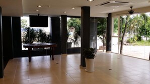 Un vestíbulo espacioso con una gran mesa, una planta en maceta y un televisor montado en la pared.