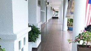 Un pasillo con paredes blancas, suelo de baldosas y plantas en macetas.