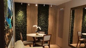 A modern dining area with a round table, chairs, and a sofa. - Hotel Água Marinha (Natal)