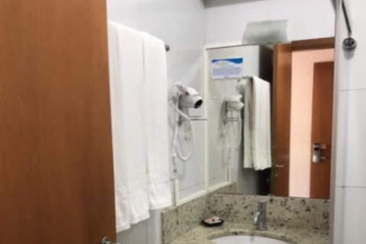 Casa de banho com lavatório, espelho, porta-toalhas e chuveiro.