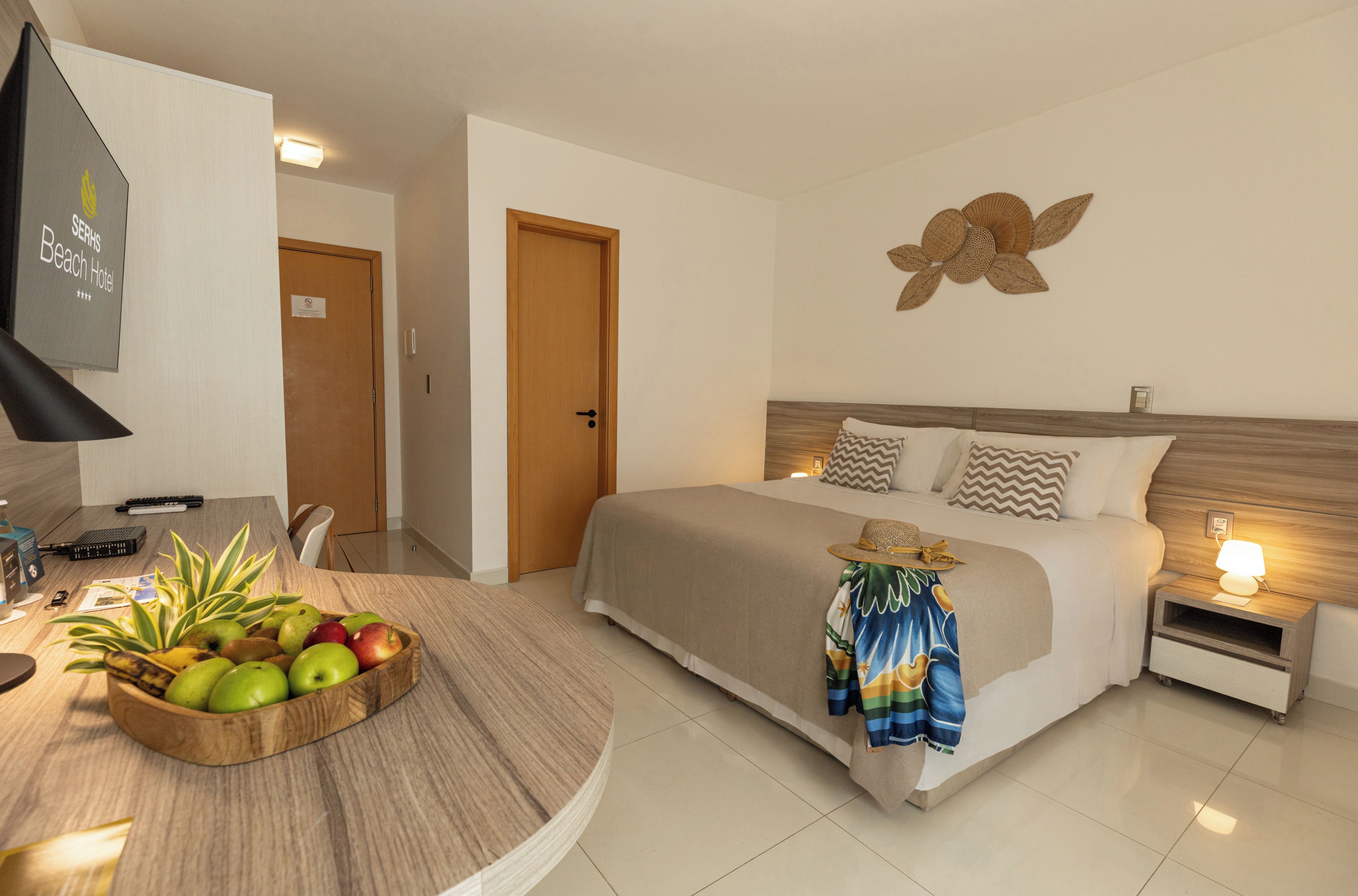 A hotel room with a bed, bedside table, lamp, and a wall decoration.
