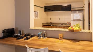 Une cuisine d’hôtel équipée d’un plan de travail en bois, d’un four à micro-ondes, d’une machine à café et d’un panier de fruits.