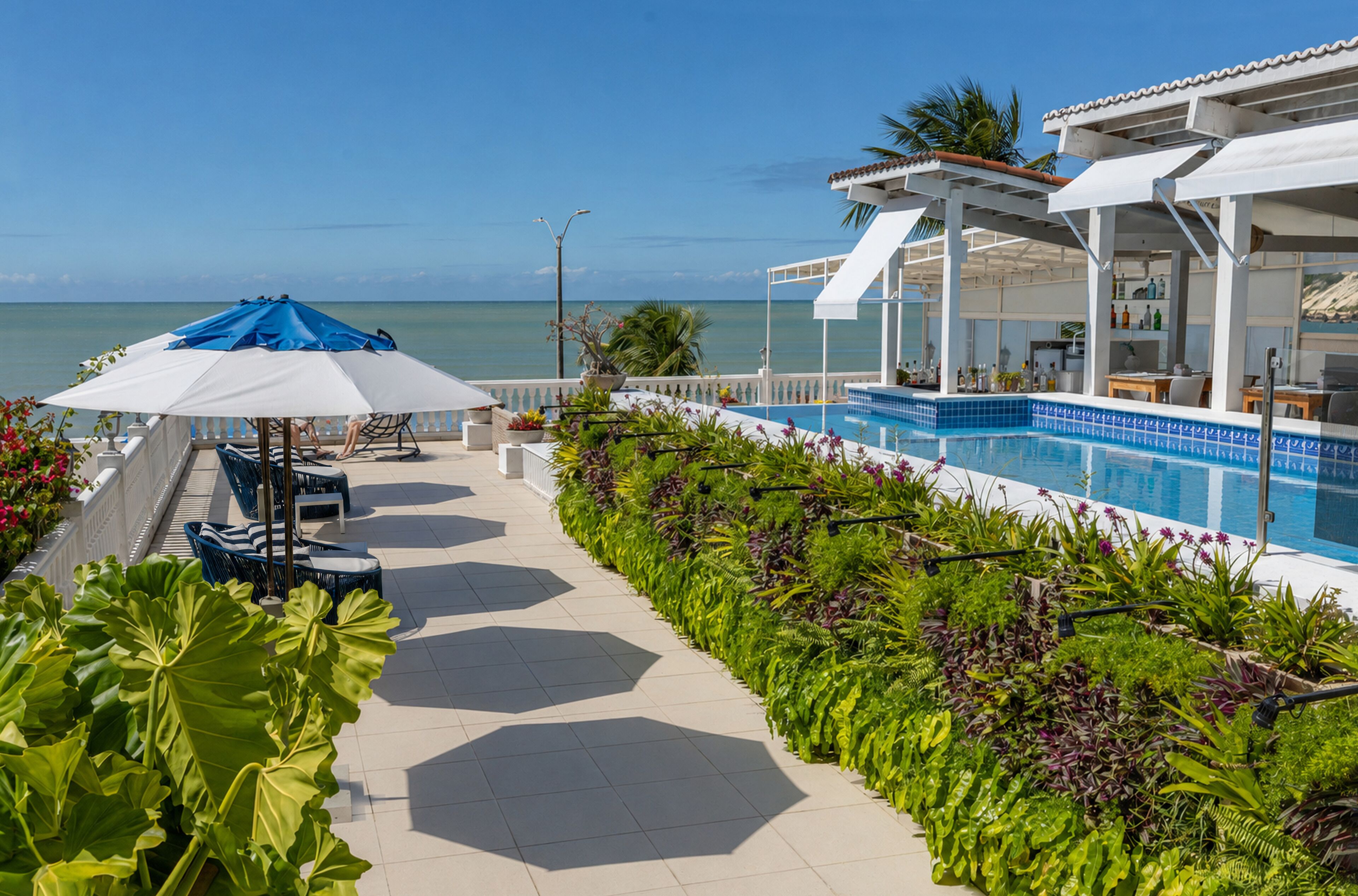 A poolside area with a view of the ocean, lounge chairs, and a bar area.