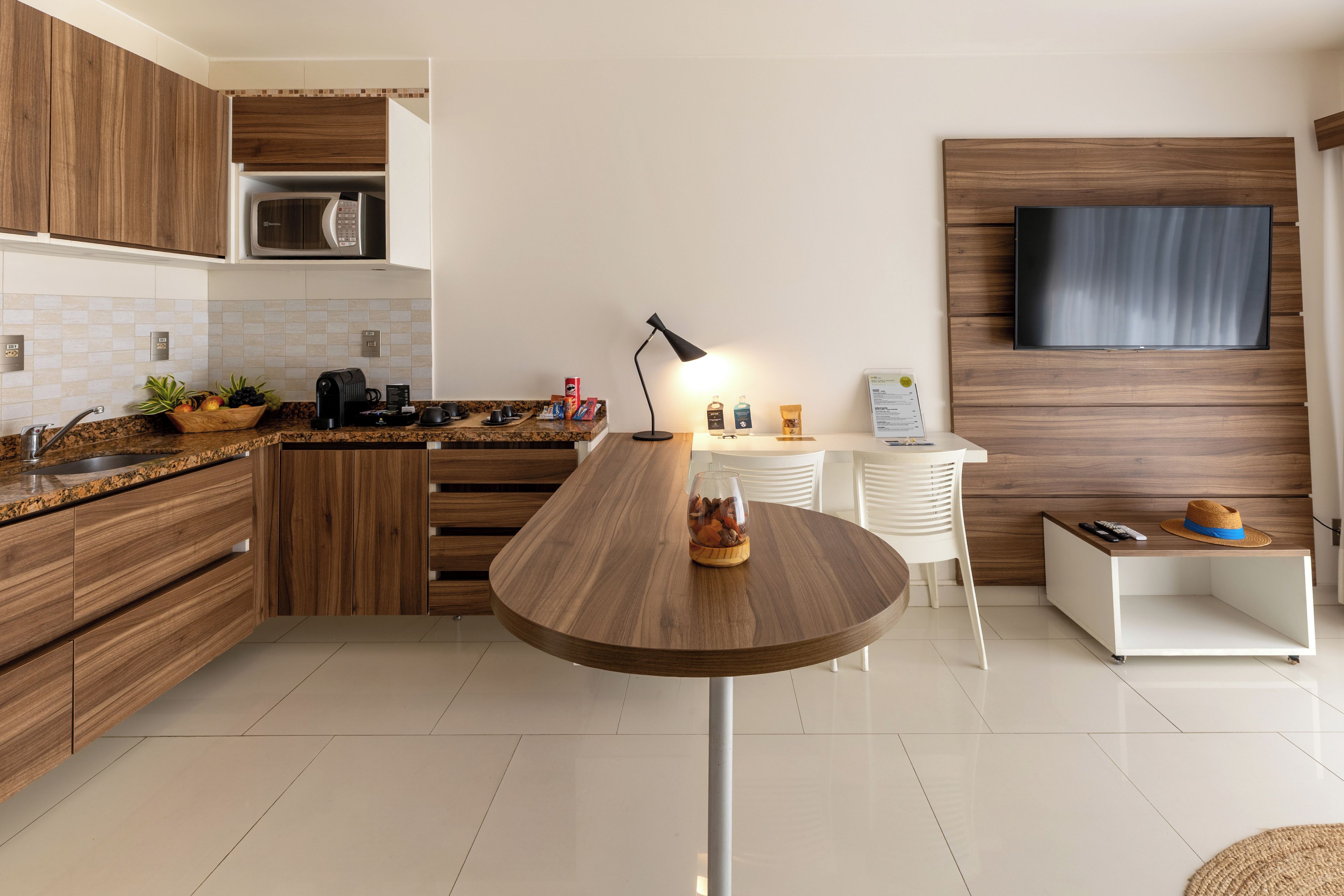 A modern kitchen with wooden cabinets, a built-in microwave, and a dining area with a round table.