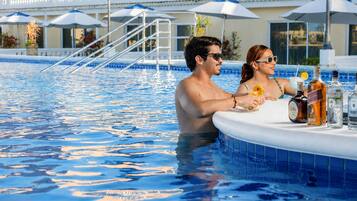 A swimming pool with a sun deck area, lounge chairs, and umbrellas.