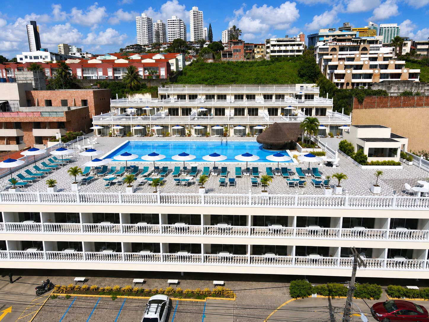 Hotel com piscina no terraço, várias varandas e estacionamento.