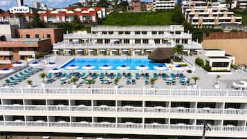 Hotel com piscina no terraço, várias varandas e estacionamento.