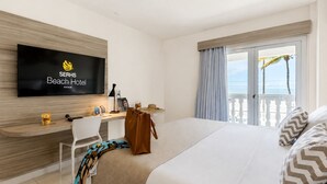 A hotel room with a bed, a desk, a television, and a view of the sea. - SERHS Beach Hotel (Natal)