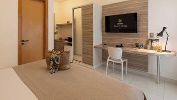 Habitación de hotel con cama, escritorio, silla, televisor y una pequeña cocina.