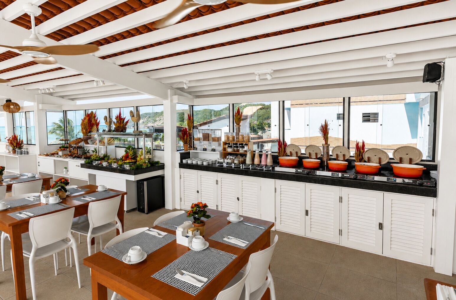 A modern restaurant with a long counter, white cabinets, and a view of the sea.