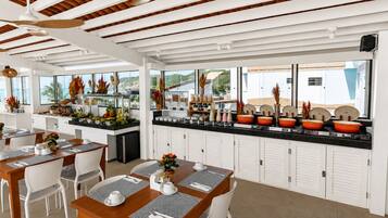 A modern restaurant with a long counter, white cabinets, and a view of the sea.
