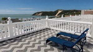 A terrace with a white balustrade, two blue lounge chairs, and a patterned floor. - SERHS Beach Hotel (Natal)