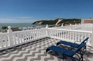 A terrace with a white balustrade, two blue lounge chairs, and a patterned floor. - SERHS Beach Hotel (Natal)