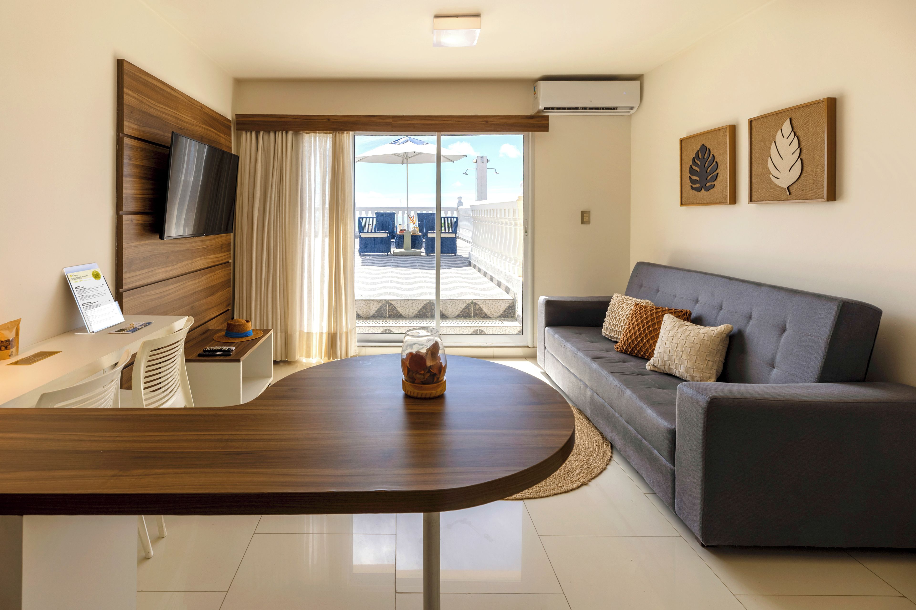 Uma sala de estar moderna com uma mesa de centro de madeira, sofá cinza e TV de tela plana montada em um painel de madeira.