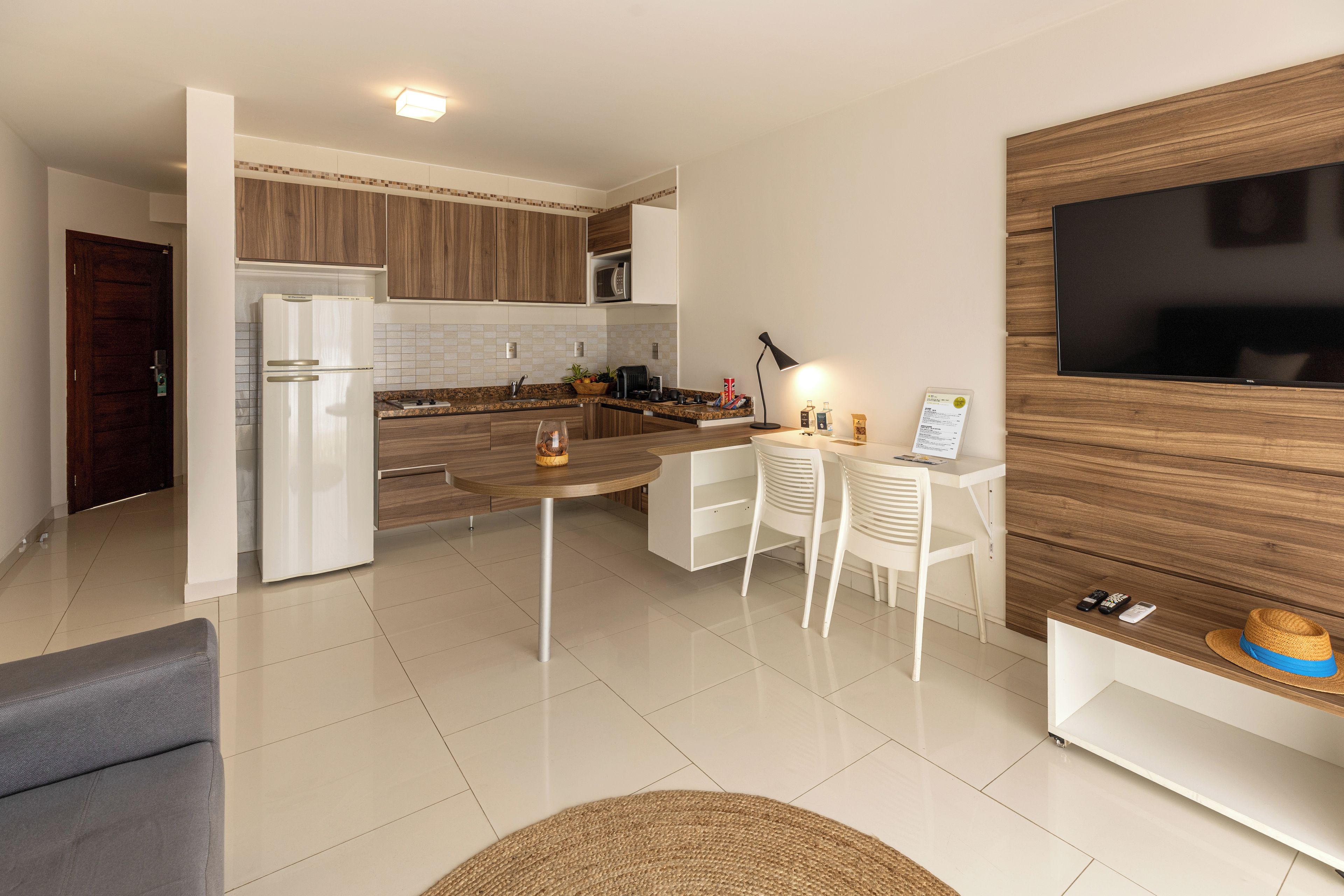 Una cocina moderna con microondas integrado, un comedor con mesa redonda y un televisor montado en una pared de madera.