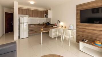 Una cocina moderna con microondas integrado, un comedor con mesa redonda y un televisor montado en una pared de madera.