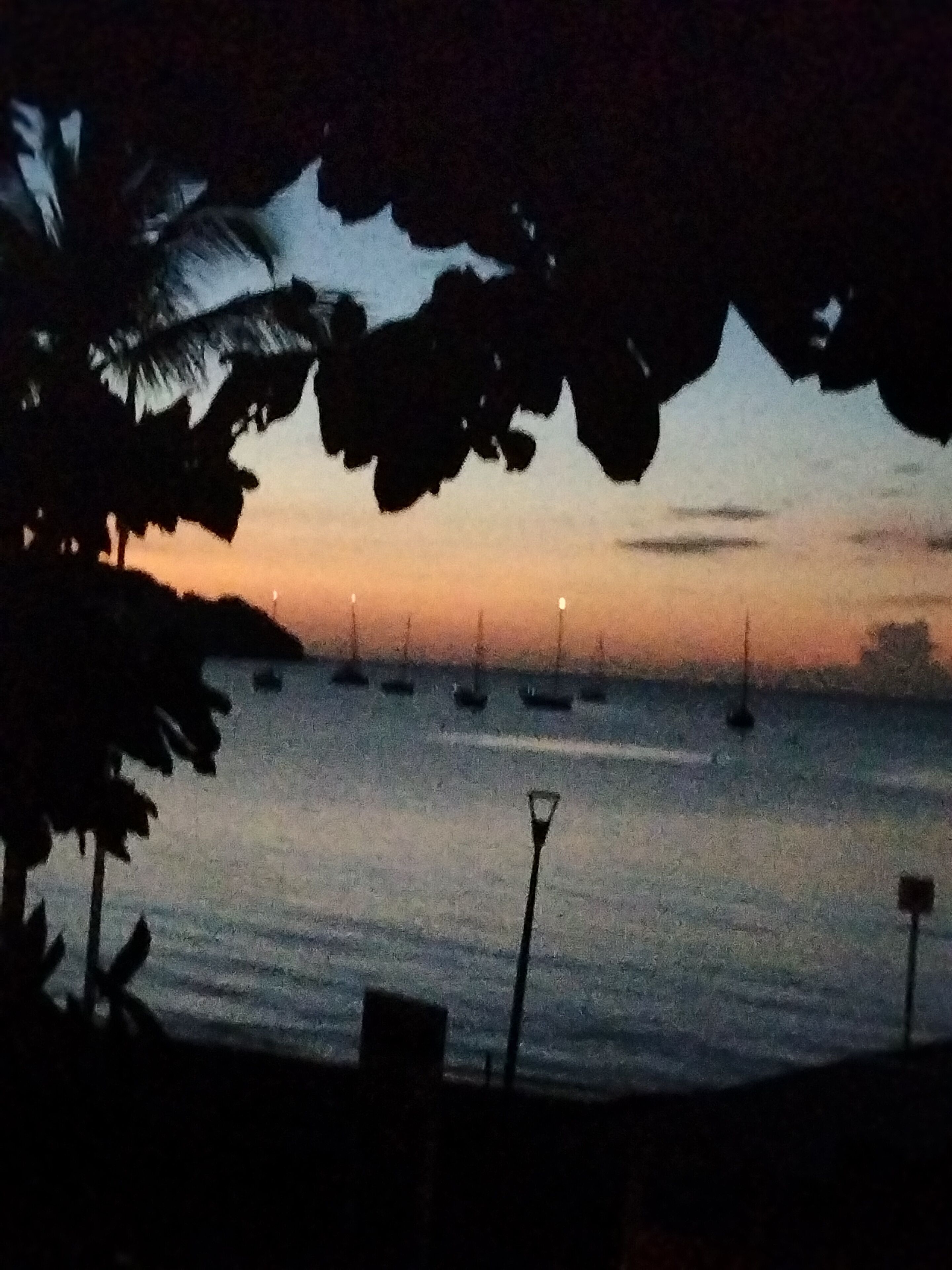 A nighttime view of a beach with boats and a street lamp.